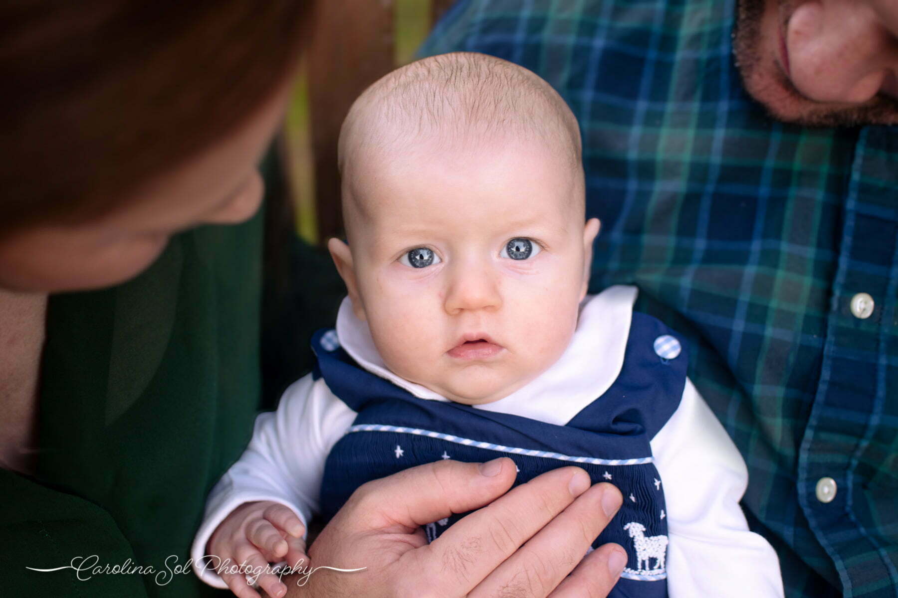 Lifestyle newborn portraits with parents holding blue-eyed son at Sunset Beach Park.