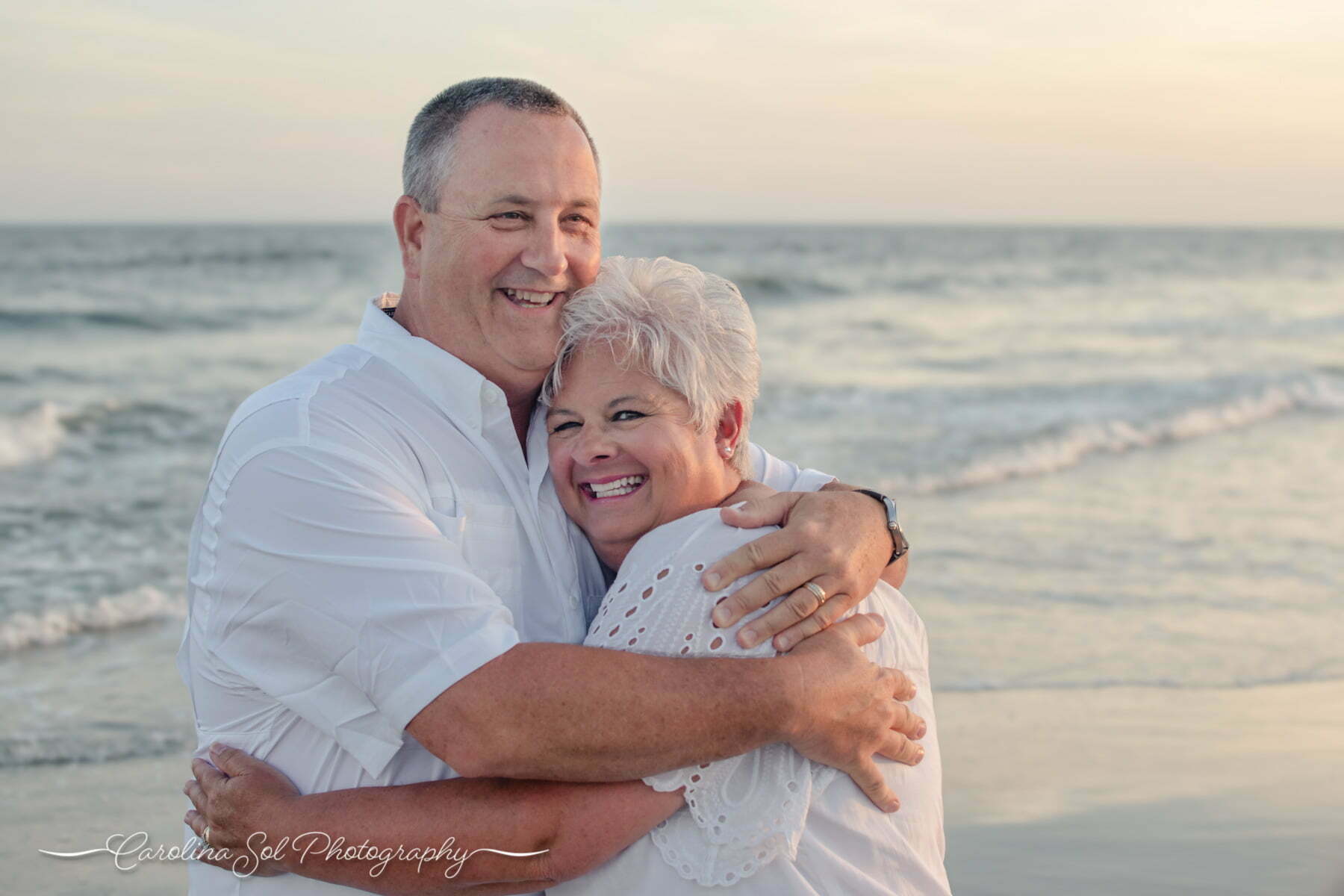 Couple beach portraits embracing lovingly during Sunset Beach photoshoot.