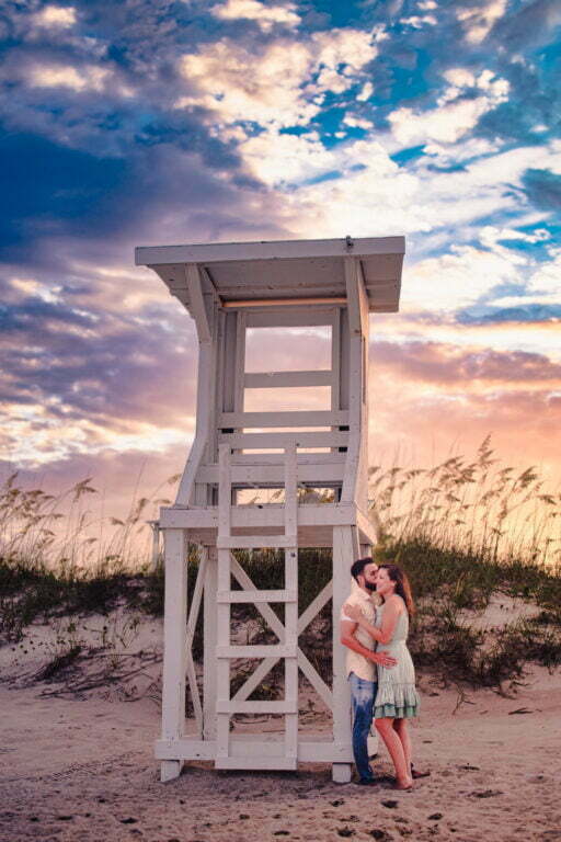 Surprise sunset proposal engagement photography session at lifeguard stand on Kure Beach, NC.